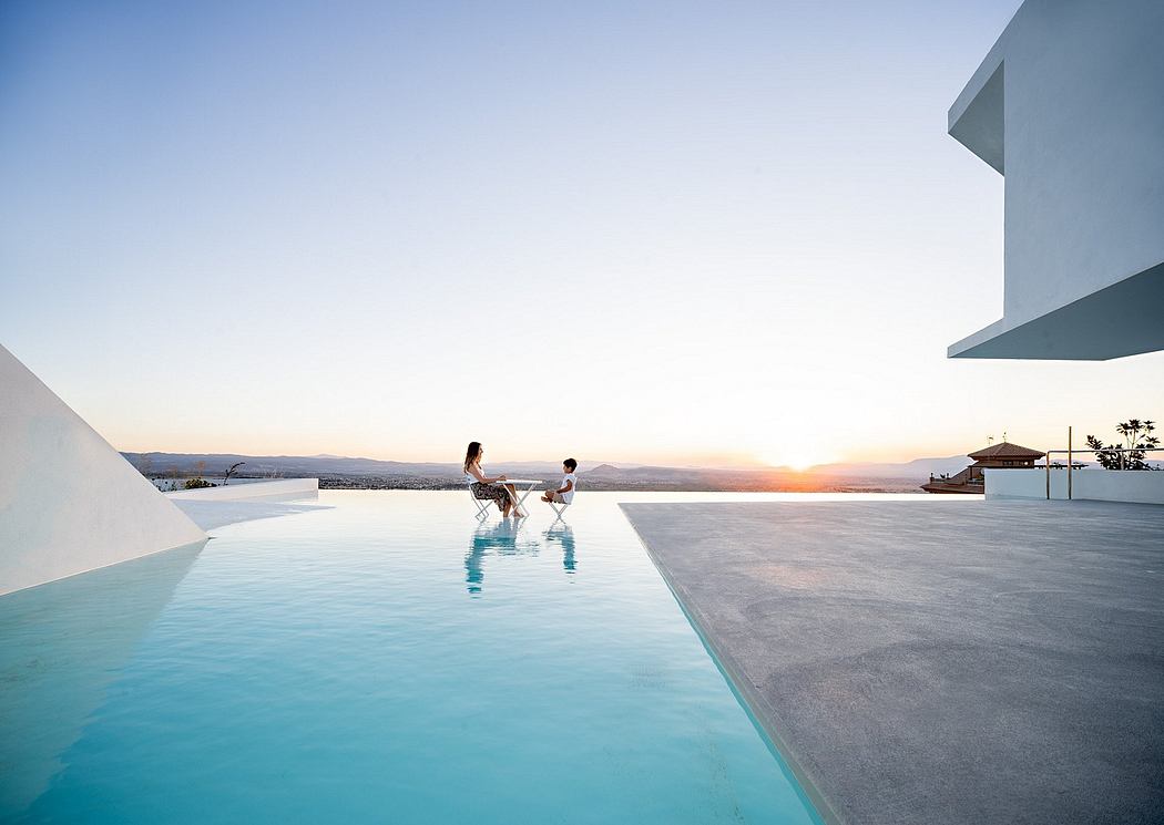 Modern architectural design with an infinity pool overlooking a scenic coastal landscape at sunset.