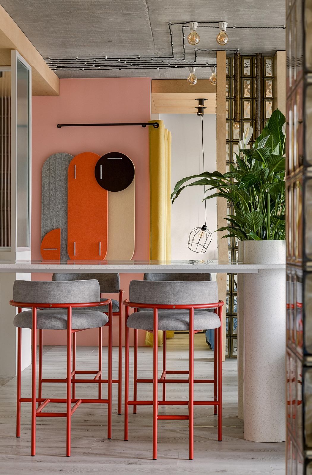Modern cafe interior with exposed ceiling, vibrant orange and yellow decor, and stylish bar stools.