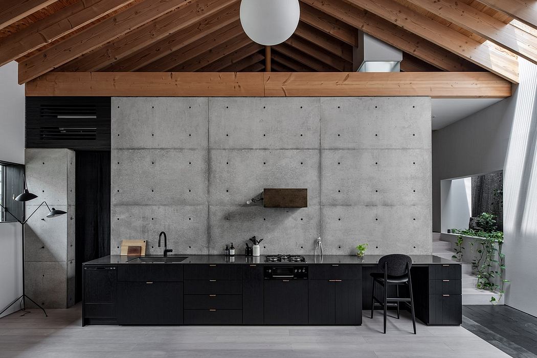 A modern kitchen with a concrete wall, black cabinets, and exposed wooden beams.
