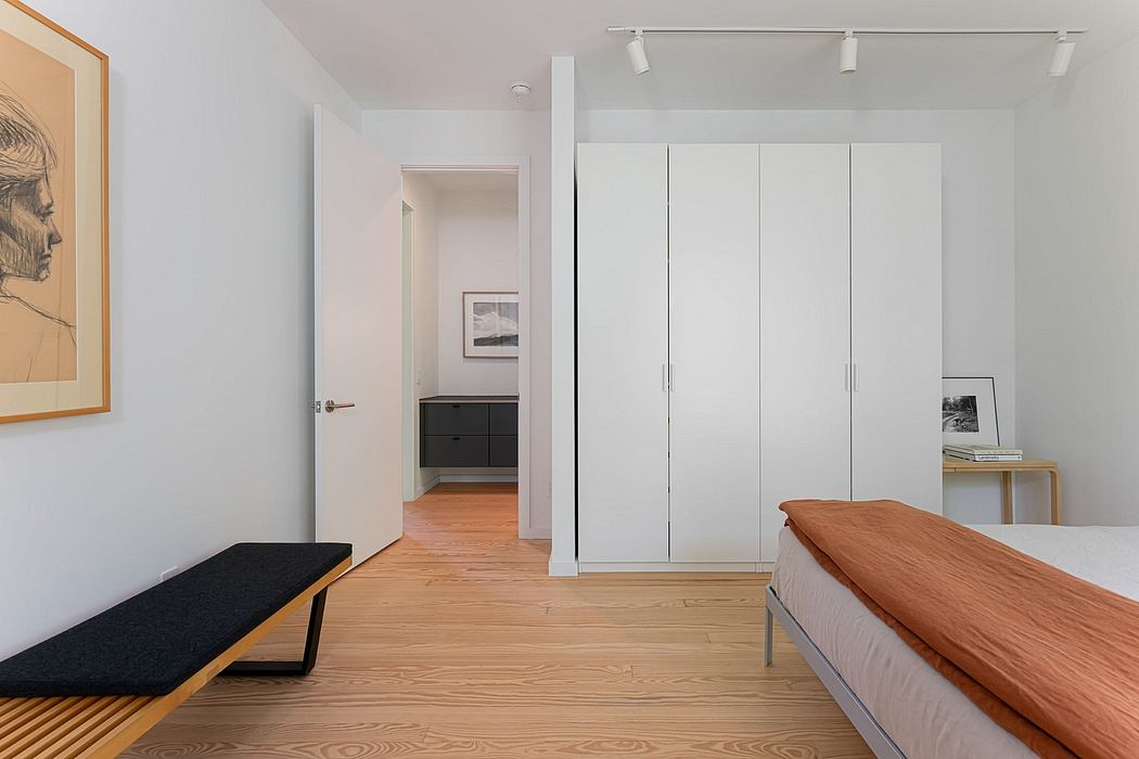 Minimalist bedroom with warm wood floors, built-in closets, and modern decor.