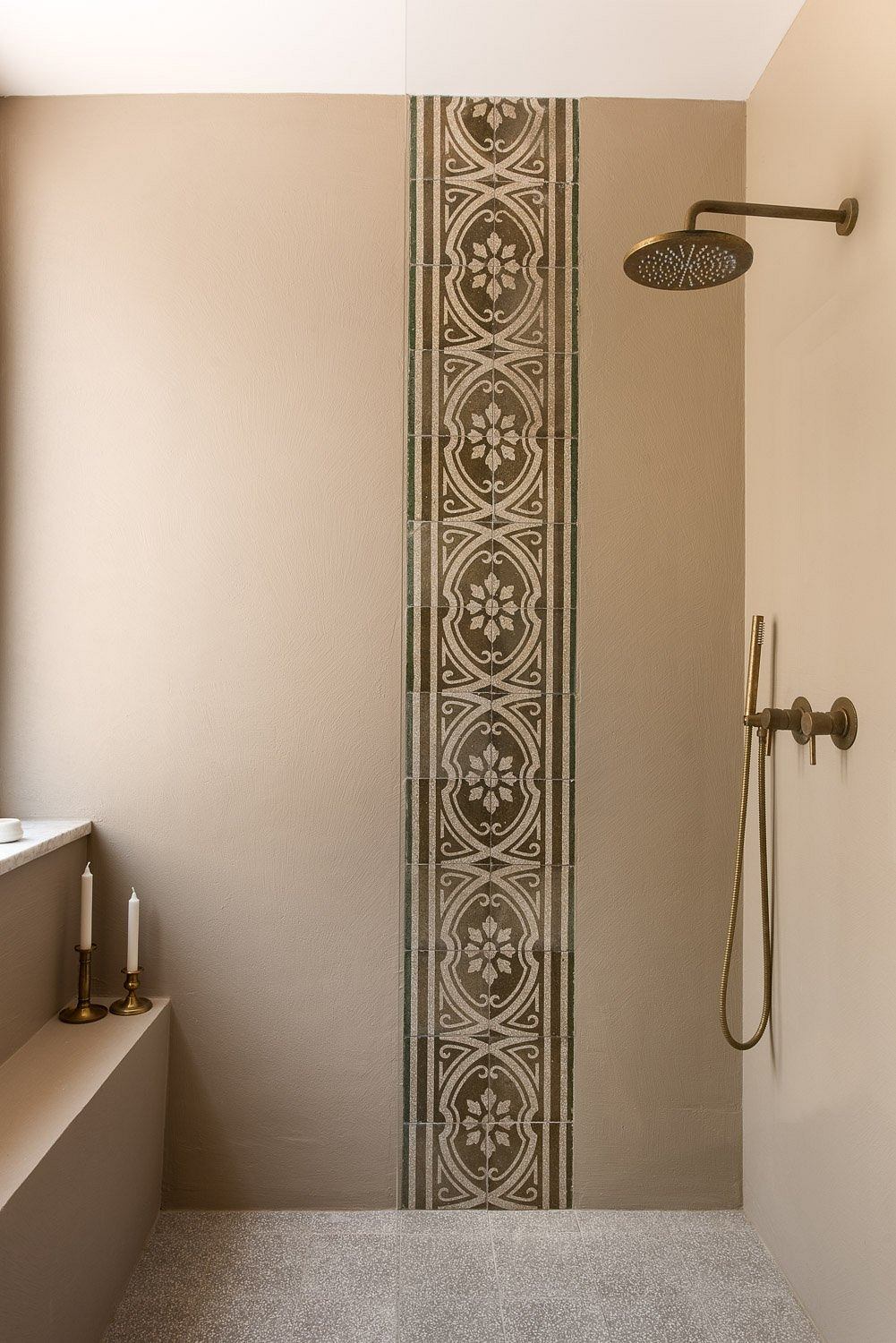 A decorative mosaic tile pattern adorns the shower wall, complementing the minimalist design.
