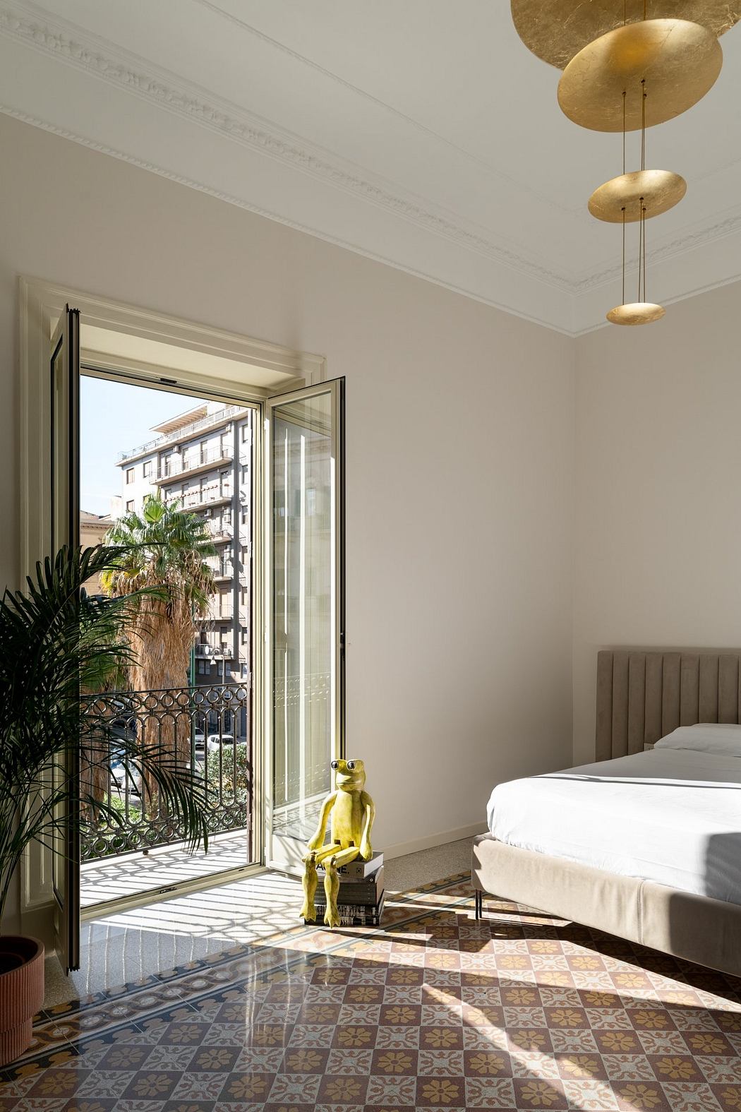 Elegant room with ornate tile floor, gold light fixtures, and a view of a balcony.