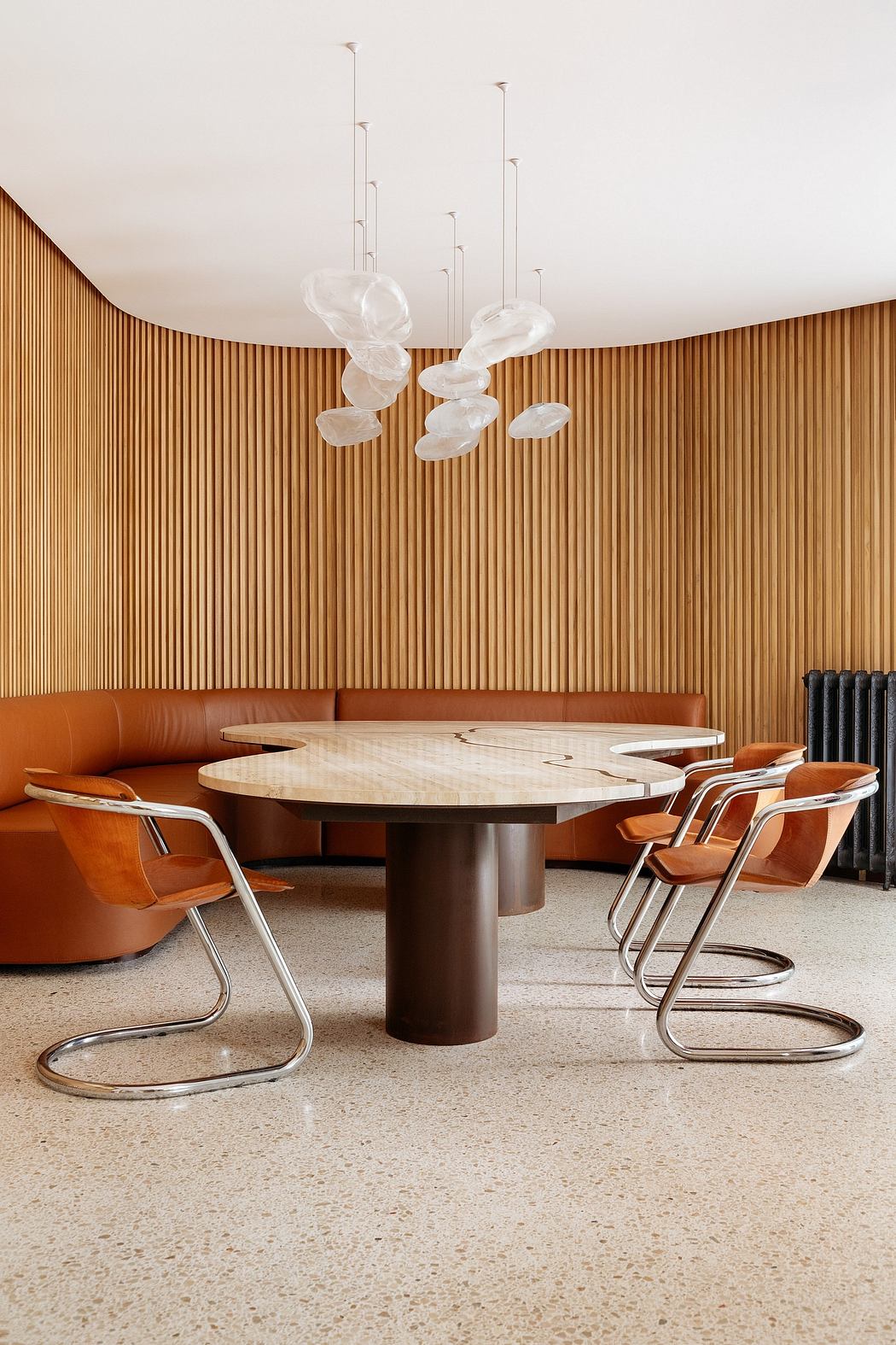 A modern dining area with a large circular table, curved leather chairs, and unique pendant lights.