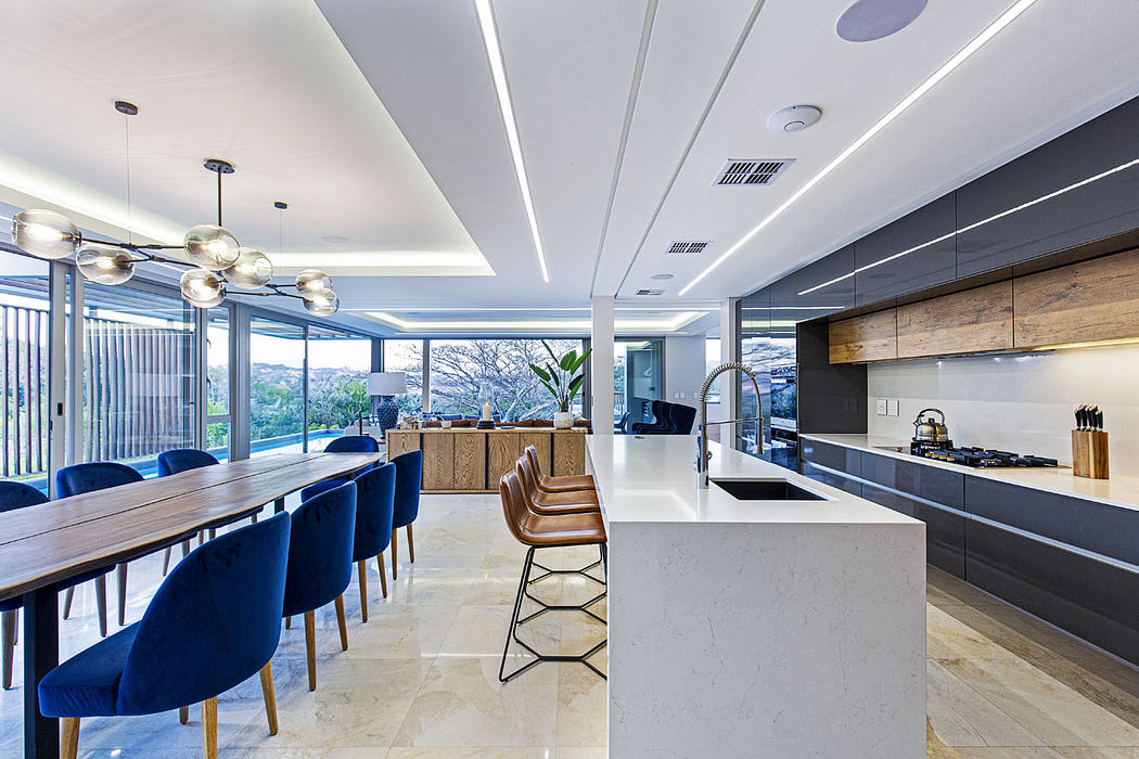 Sleek, modern kitchen with marble countertops, pendant lighting, and a large dining table.