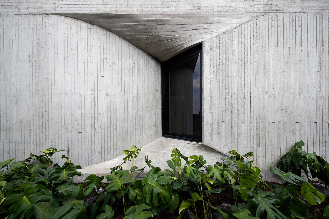 A modern concrete structure with lush greenery growing around its entrance, creating a striking contrast.
