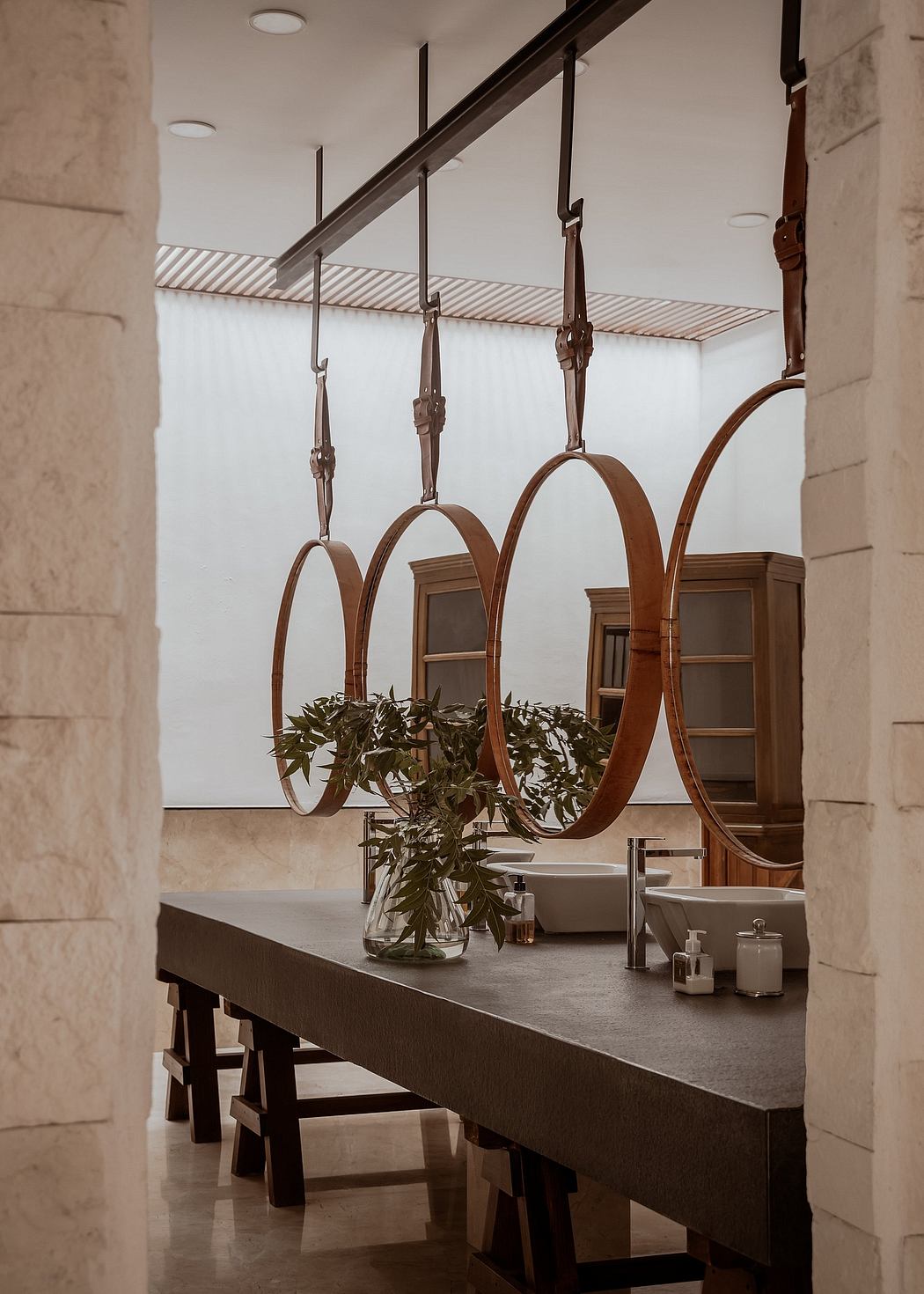 A minimalist dining area with vintage-style metal light fixtures and a stone wall.