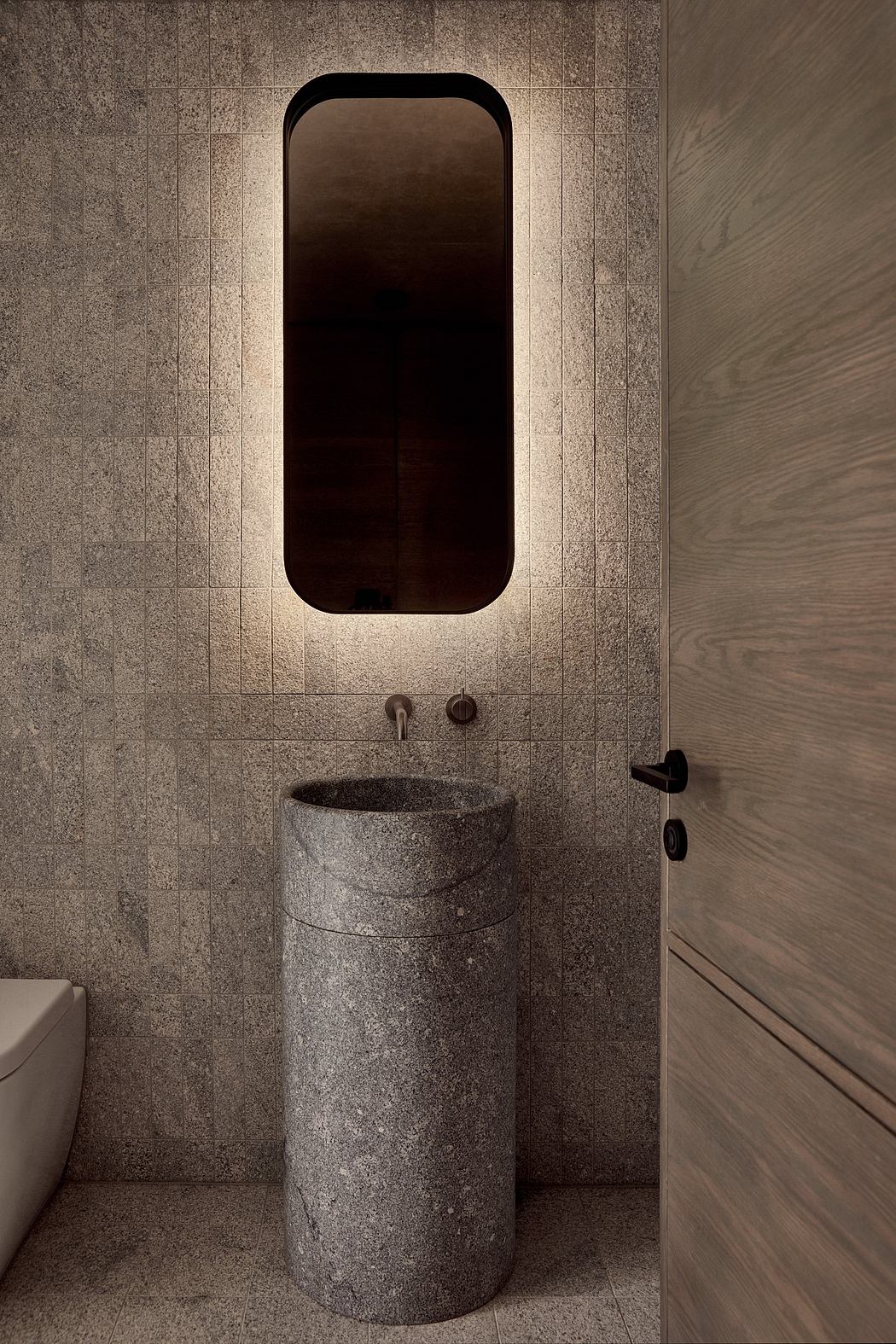A modern, minimalist bathroom with a large arched mirror, a freestanding stone basin, and simple fixtures.