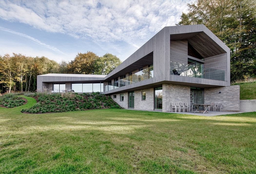 A sleek, modern house with a striking roofline, extensive glazing, and lush landscaping.
