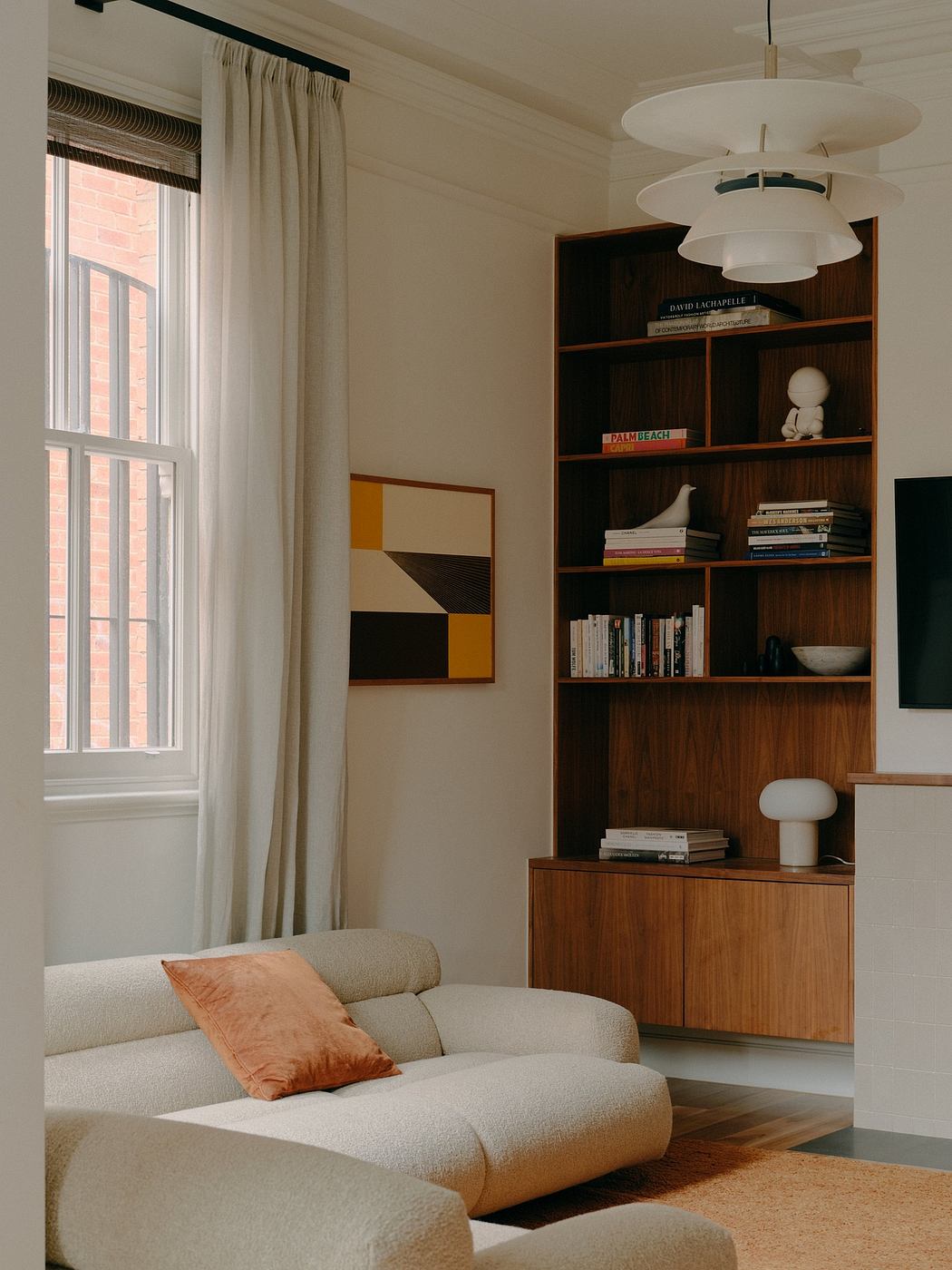 Cozy living room with wooden shelving, textured artwork, and warm lighting.