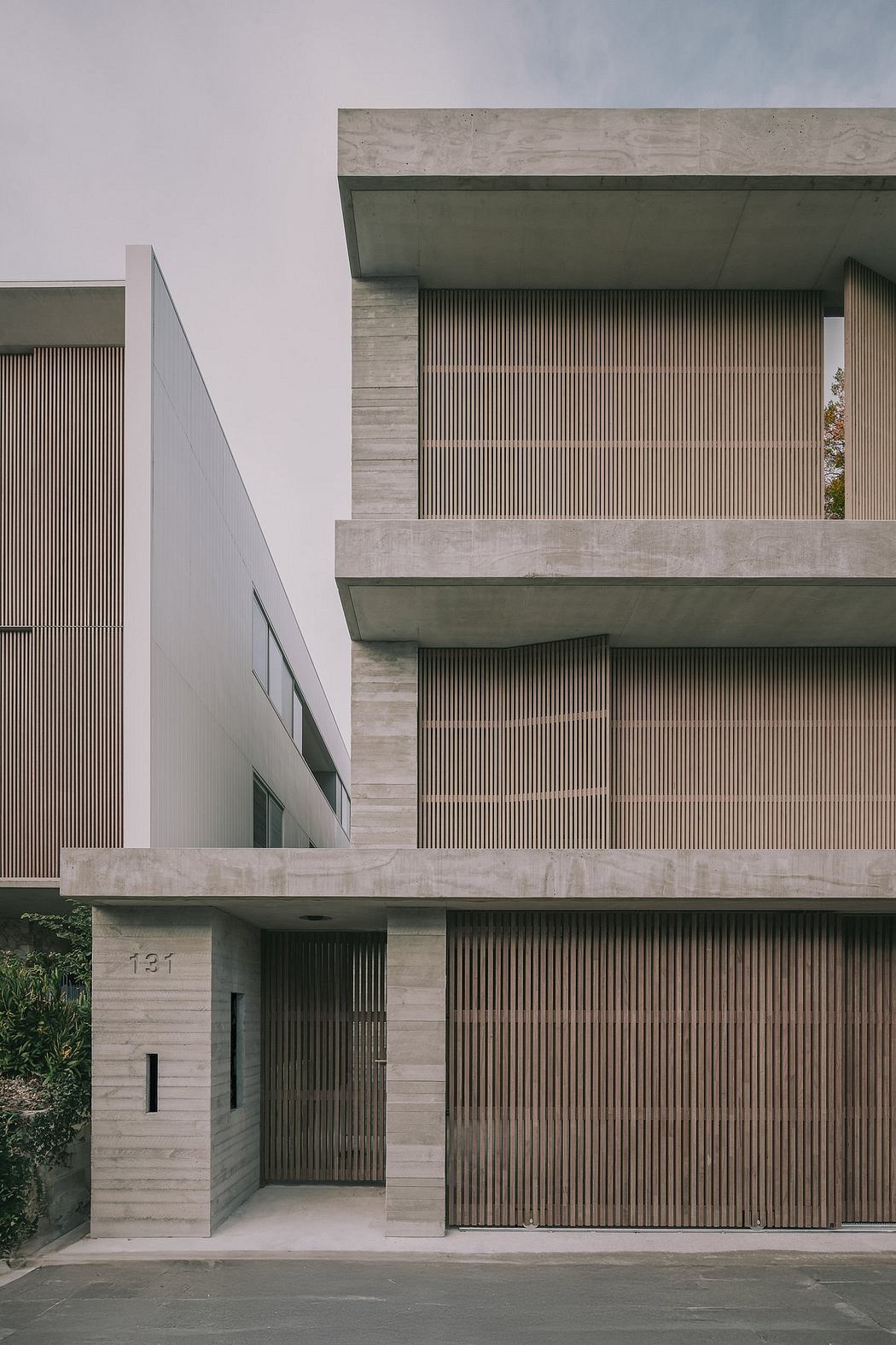 A modern, minimalist building with concrete, wood, and glass elements, featuring clean lines and a visually striking facade.