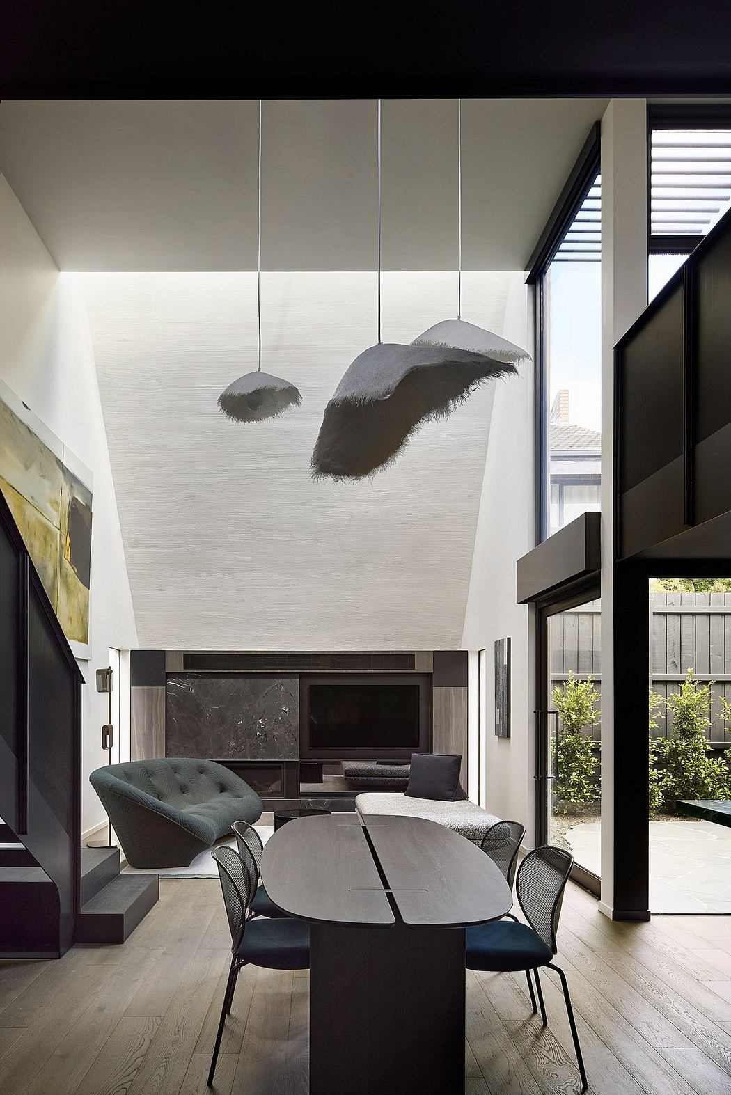Minimalist living space with pendant feather lamps, modern furnishings, and large windows.