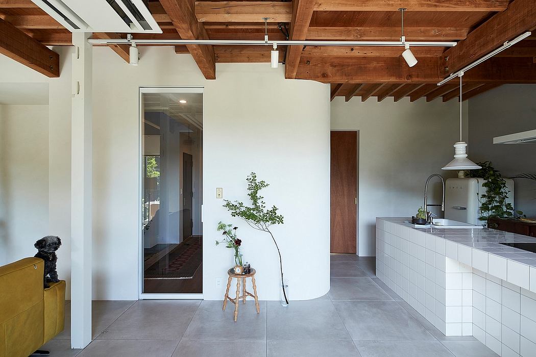 Rustic wooden beams, modern kitchen with white cabinetry, and a minimalist floral accent.