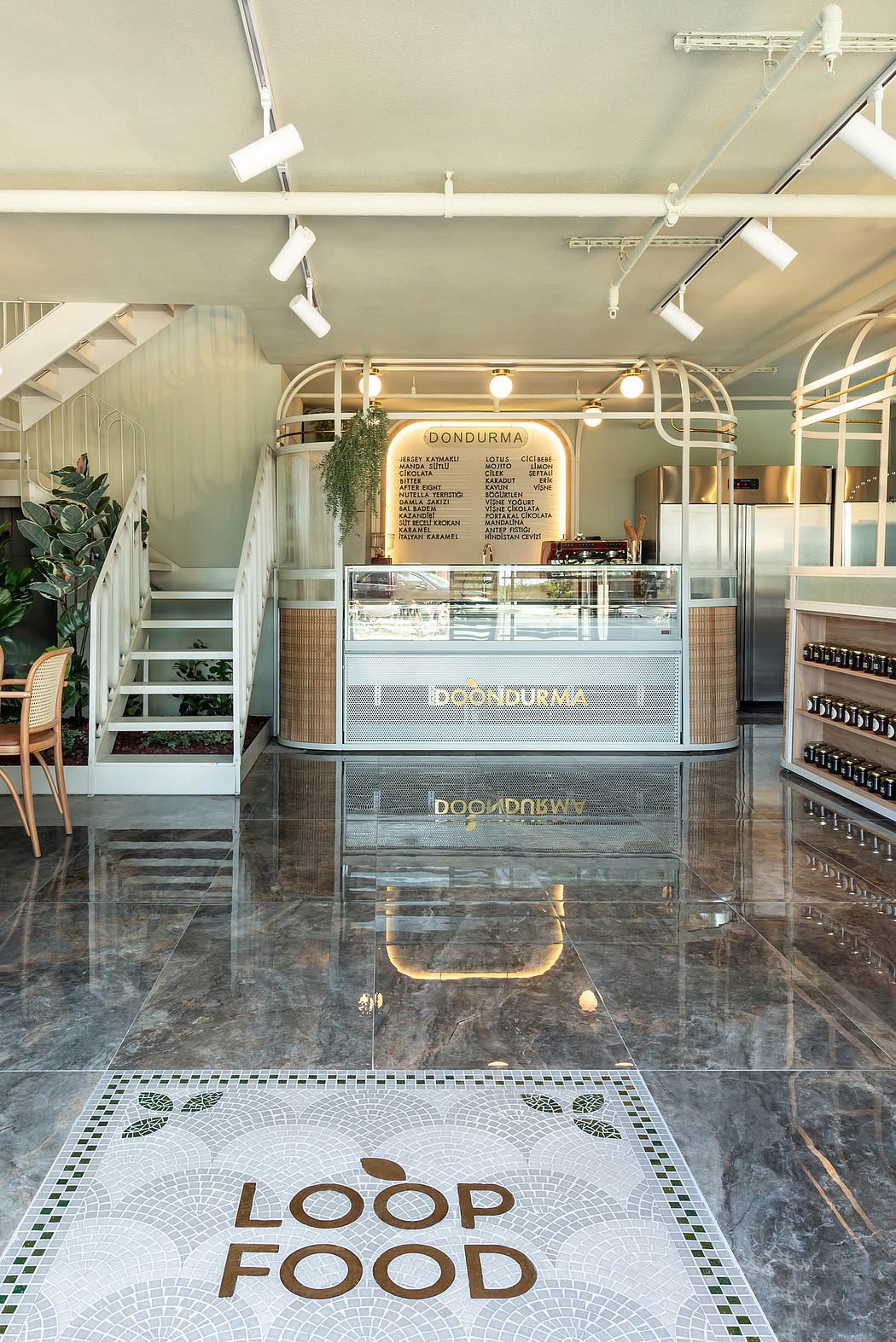 A modern and minimalist cafe interior with a sleek counter, mosaic floor, and track lighting.