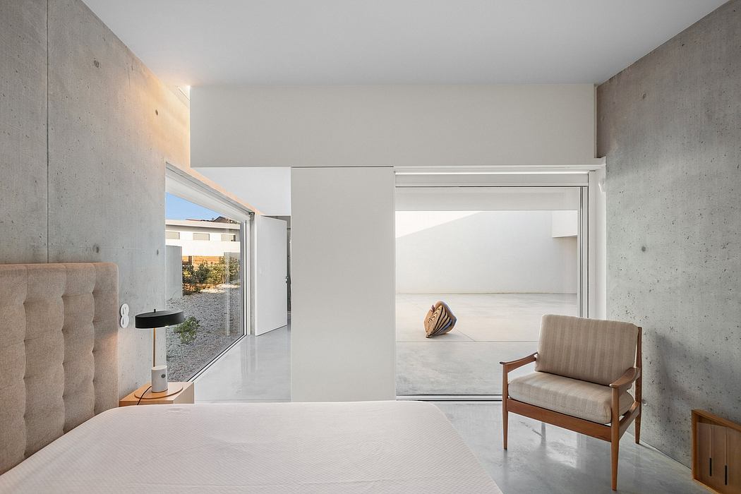 Minimalist interior with concrete walls, wooden furniture, and expansive windows.
