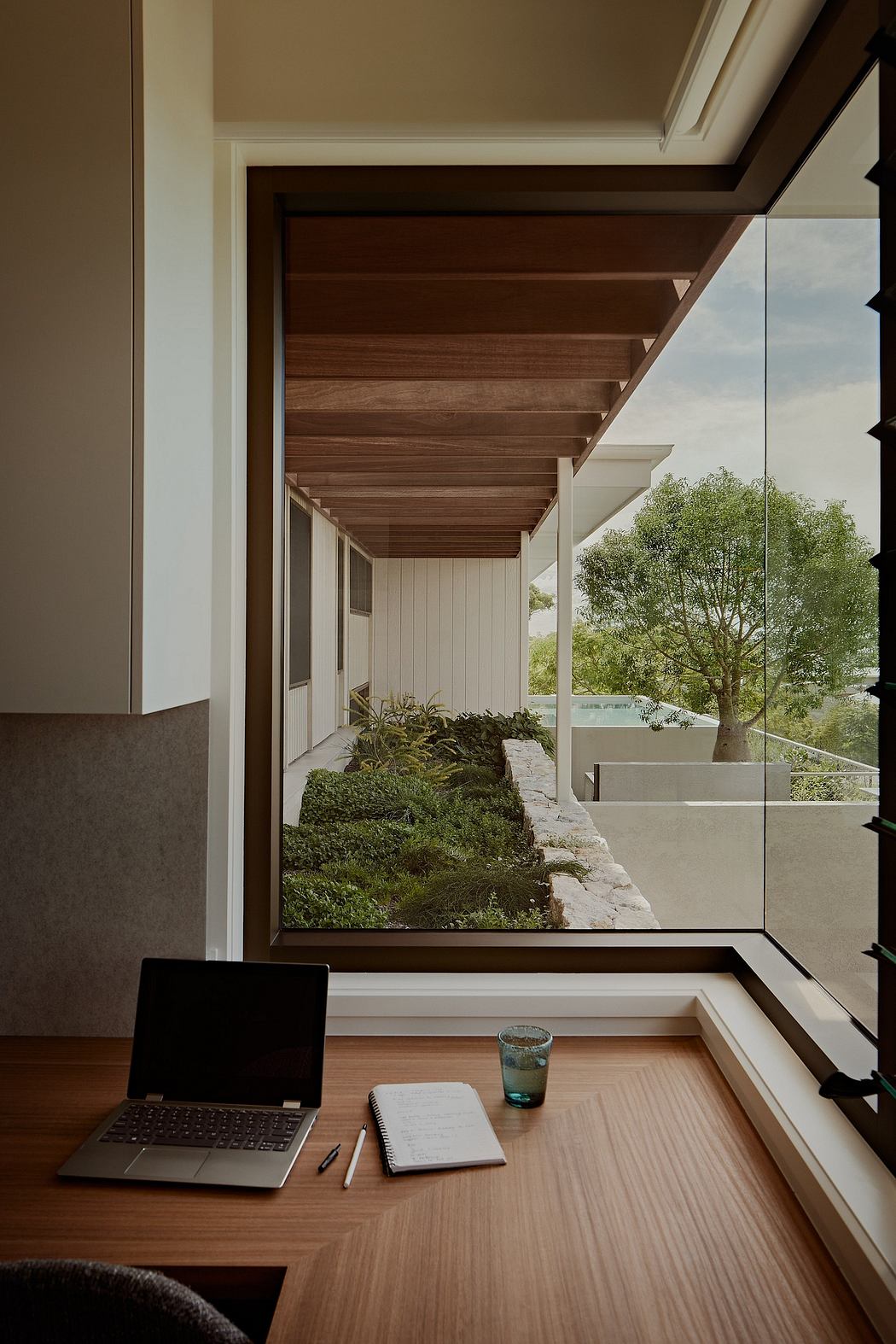 Sleek wooden beams, expansive windows, and lush greenery create a tranquil workspace.