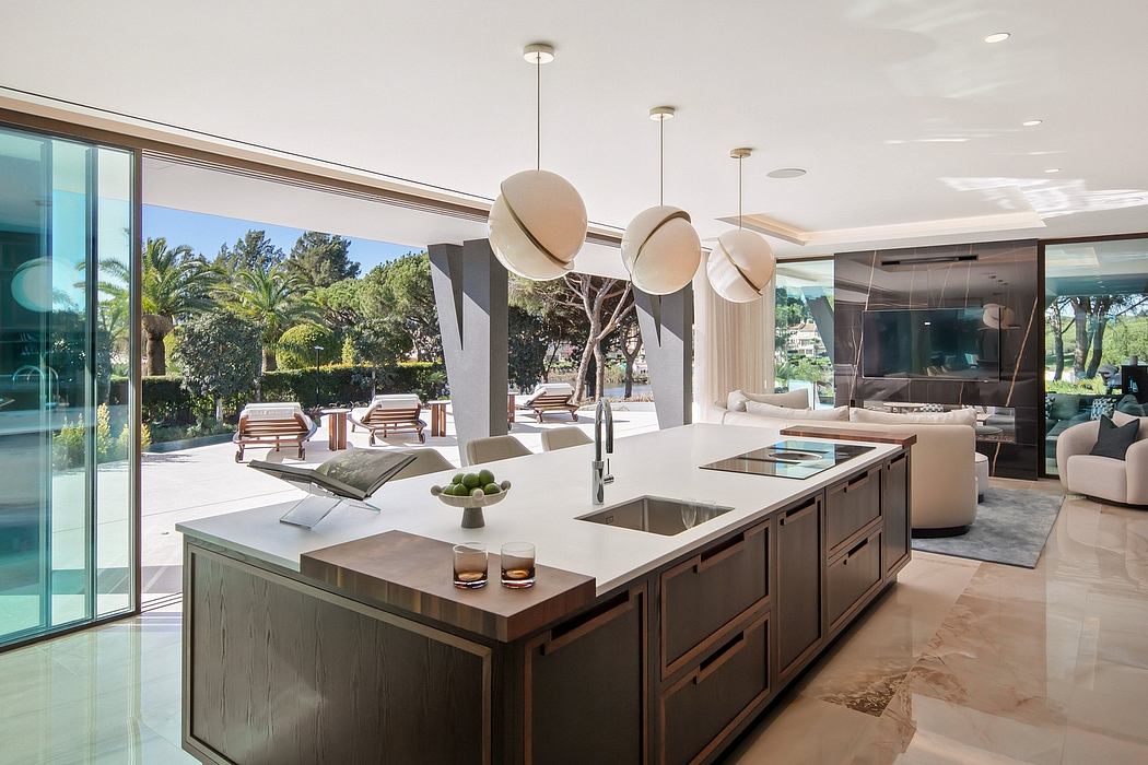 Sleek, modern kitchen with a large island, pendant lighting, and views of a lush outdoor space.