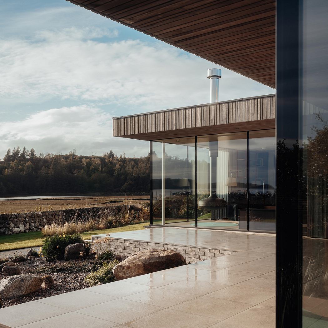 Contemporary architecture with wooden roof, glass walls, and stone landscape features.