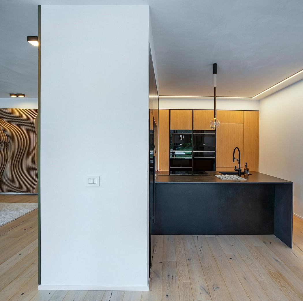 A modern kitchen with sleek black countertops, warm wood cabinetry, and minimalist lighting.
