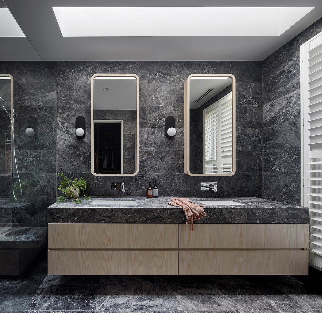 Luxurious bathroom with dark marble walls, recessed lighting, and mirrored vanity.