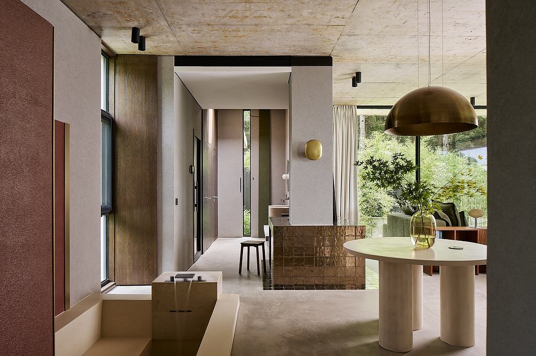 Contemporary open-plan living space with exposed concrete ceiling, bronze lighting, and minimalist furniture.