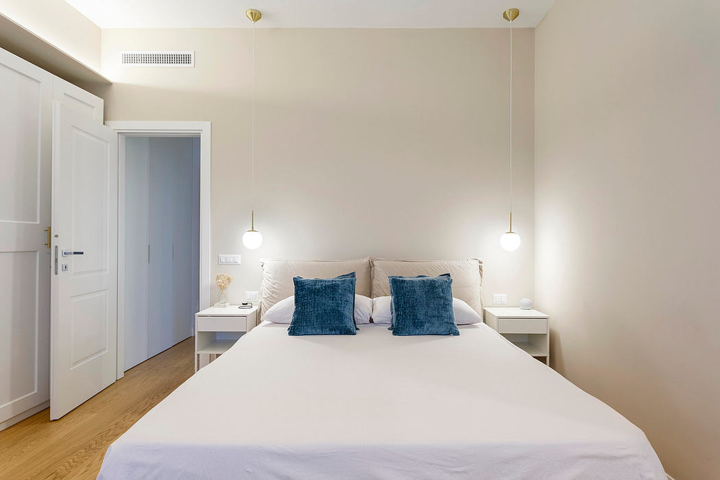 Cozy bedroom with minimalist decor, white walls, hardwood floors, and pendant lighting.