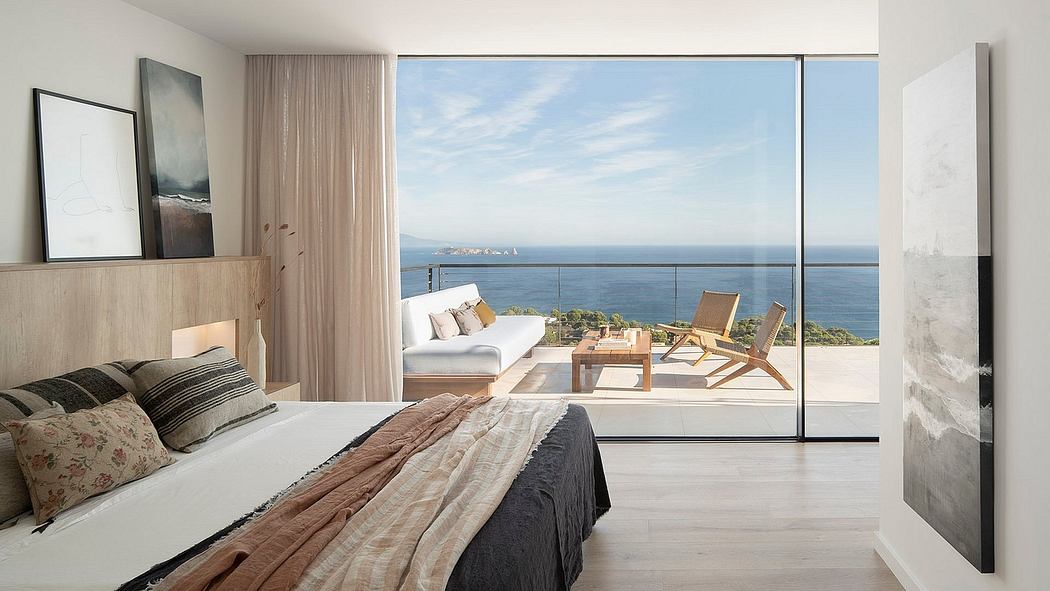 Modern bedroom with panoramic ocean view, minimalist furnishings, and expansive windows.