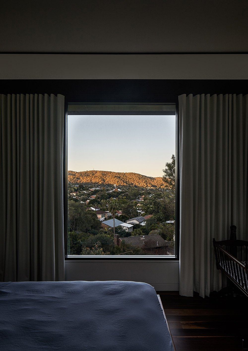 A room with large windows overlooking a scenic mountain landscape, with dark curtains framing the view.