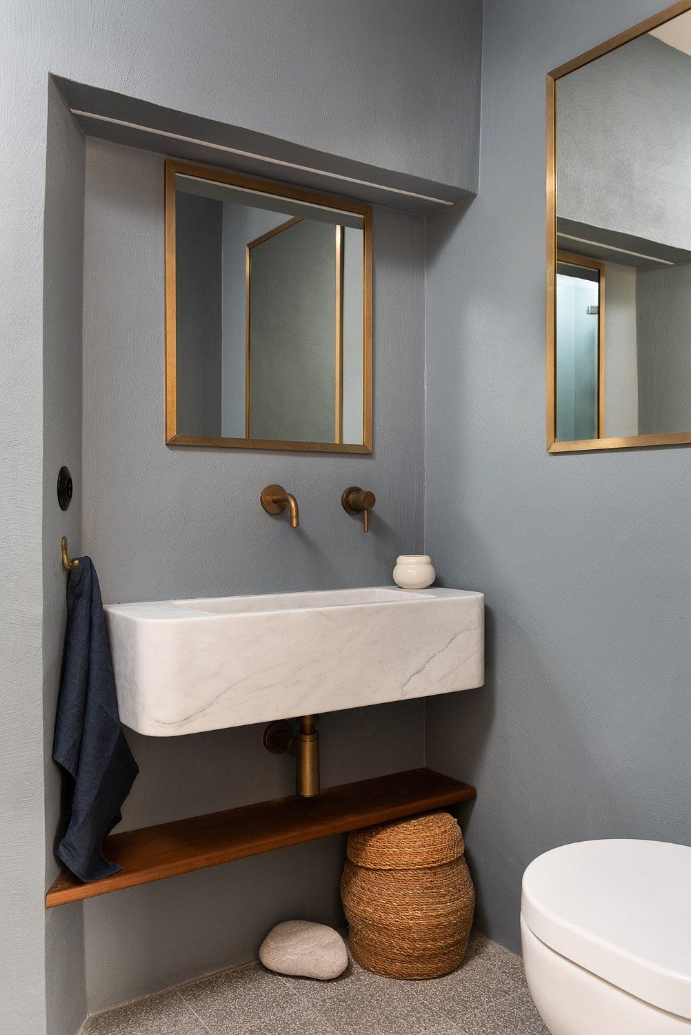 Contemporary bathroom with sleek gray walls, metallic fixtures, and natural accents.