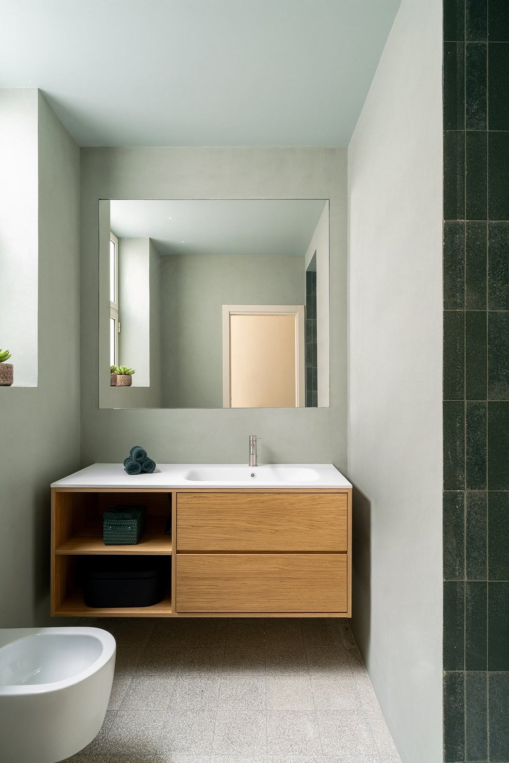 Minimalist bathroom with wooden vanity, white ceramic sink, and square mirror.