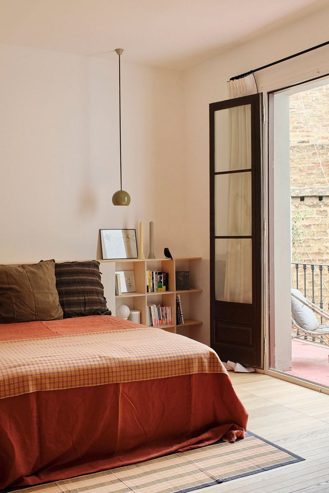 Cozy bedroom with wood-framed glass door, pendant light, and built-in shelving.