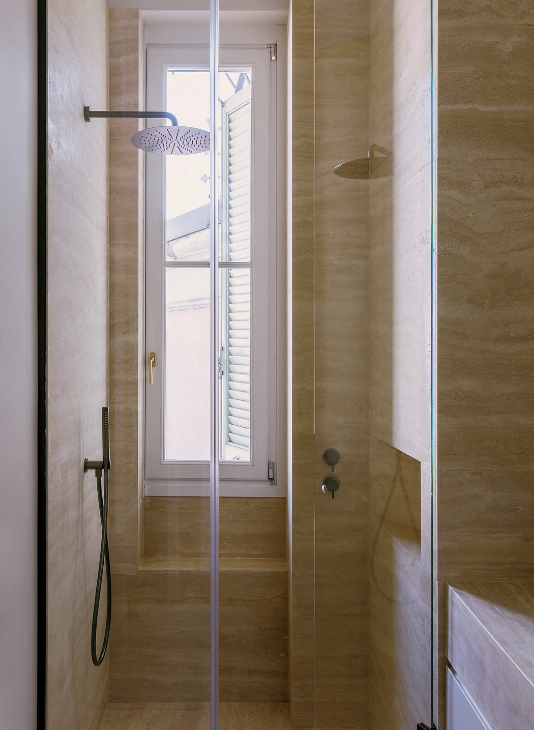 A modern bathroom with a glass-enclosed shower and a large window allowing natural light.