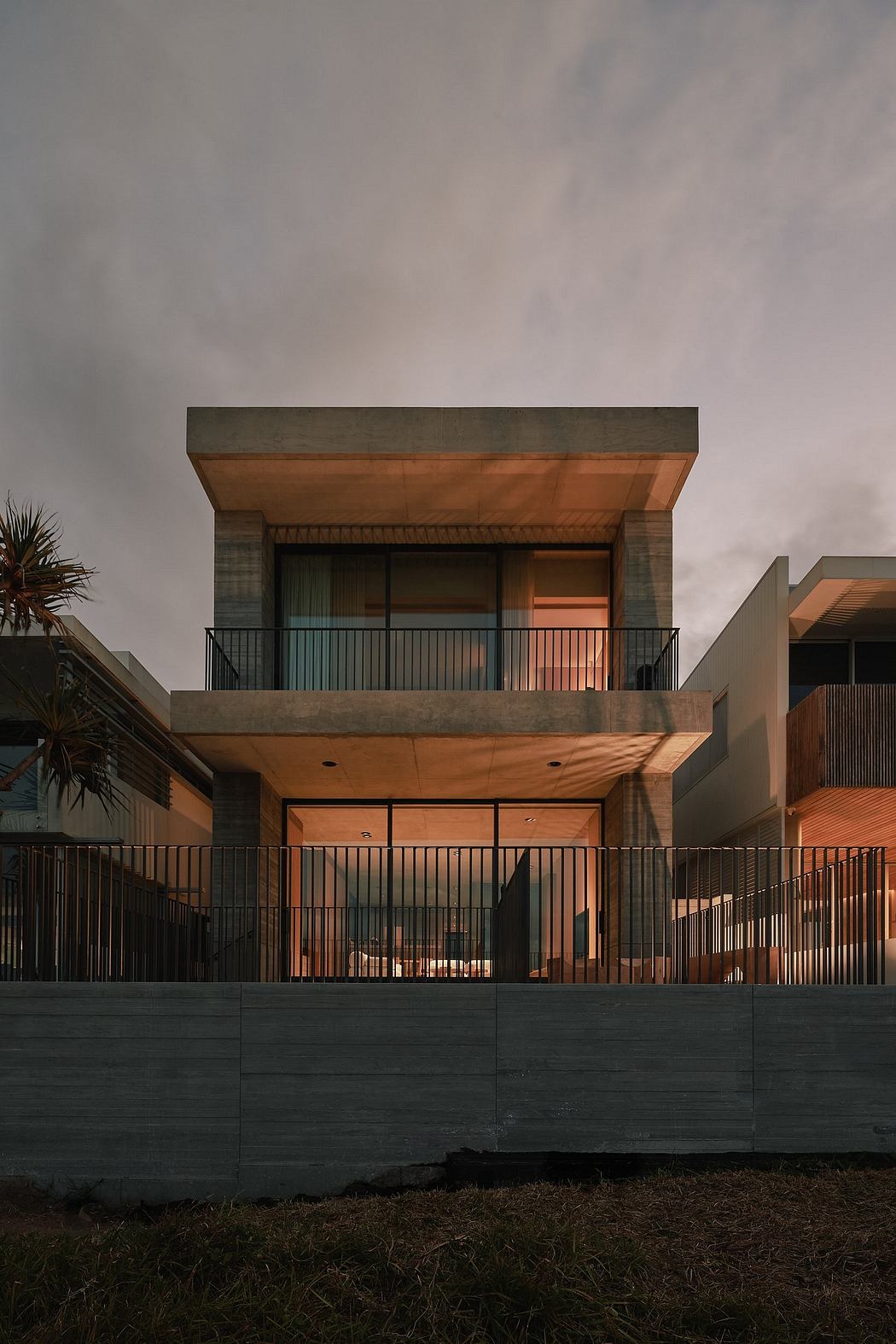 A modern, multi-level residence with a wooden-clad exterior, balconies, and metal fencing.