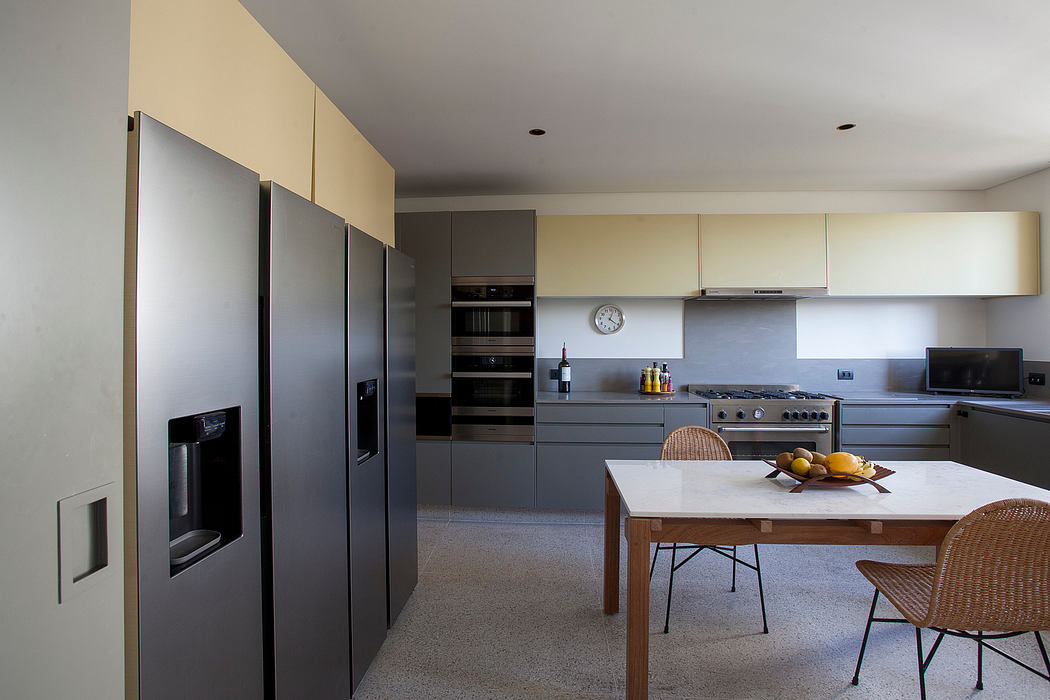 Modern kitchen with sleek gray cabinets, stainless steel appliances, and a large dining table.