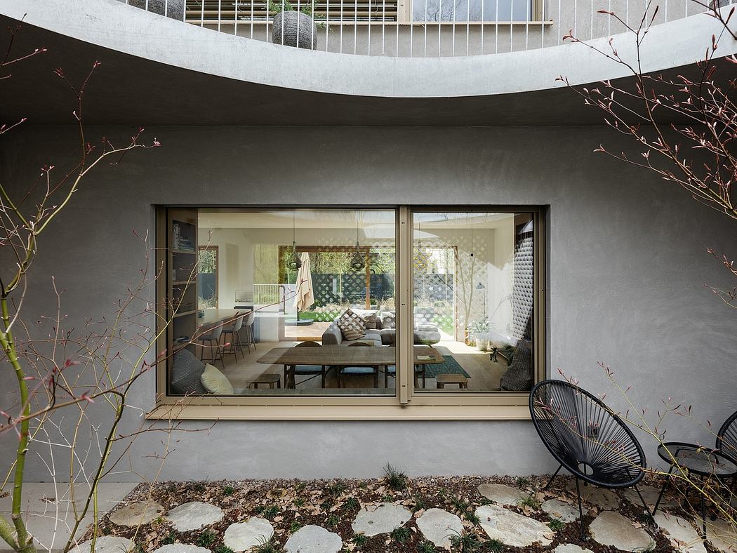 Curved concrete facade frames a modern dining and living space with large windows.