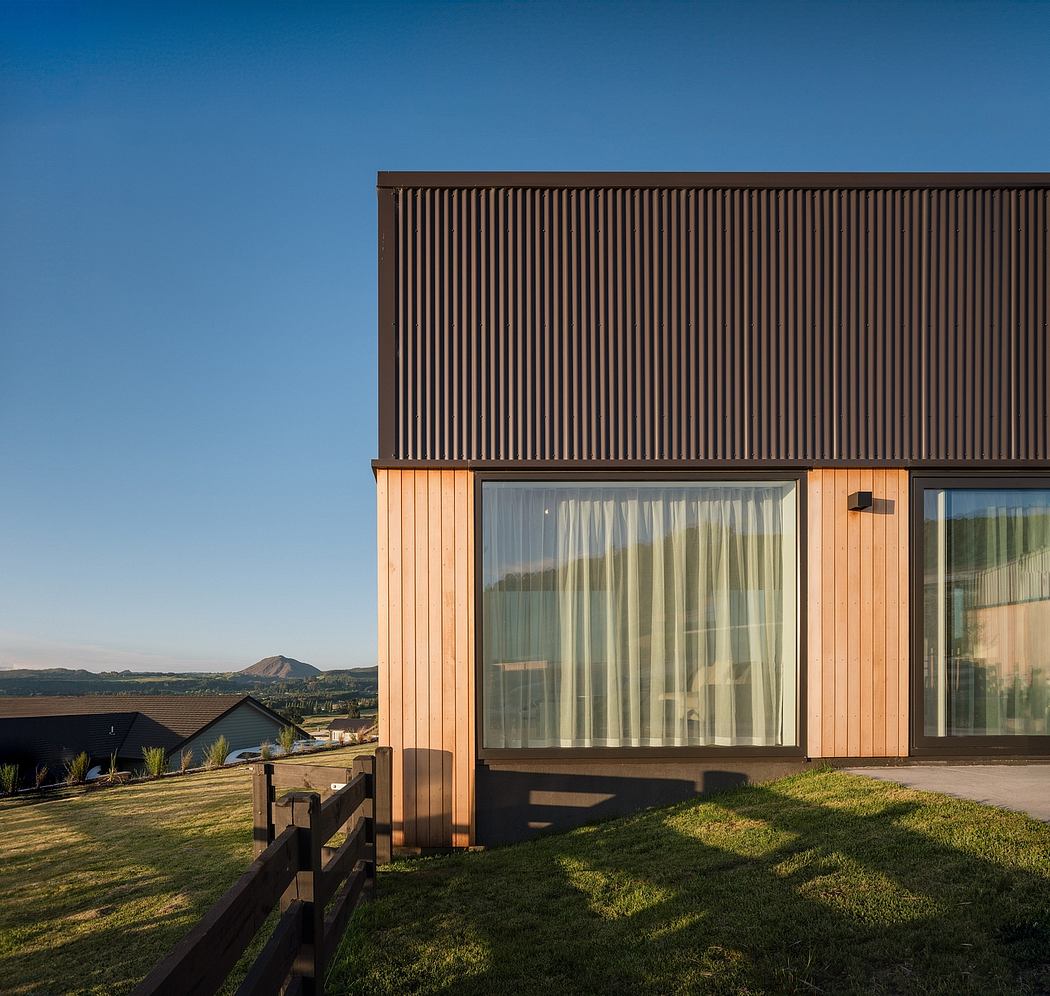 Contemporary wooden exterior with striped paneling and large windows overlooking a grassy landscape.