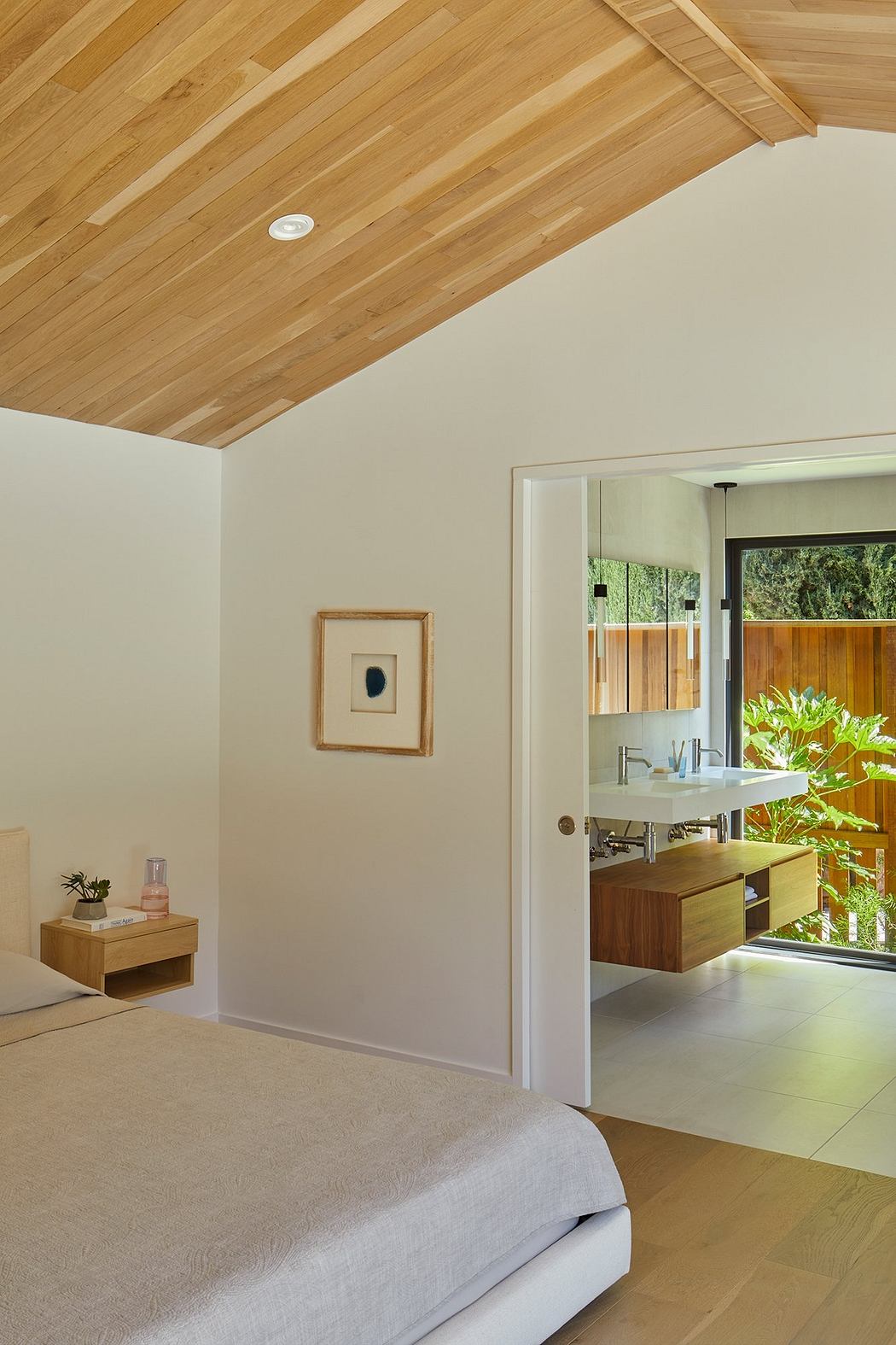 Warm wooden ceiling, neutral walls, and modern vanity with outdoor views in bathroom.