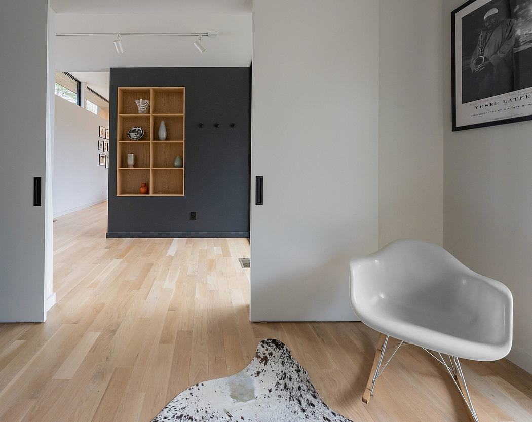 Modern minimalist interior with wooden shelving, hardwood floors, and white chair.