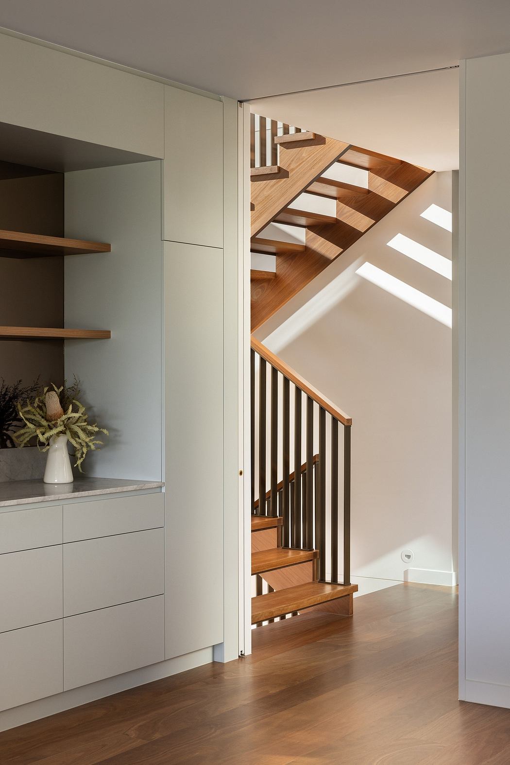 Modern staircase with wooden steps and metal railings, complementing the minimalist shelving.