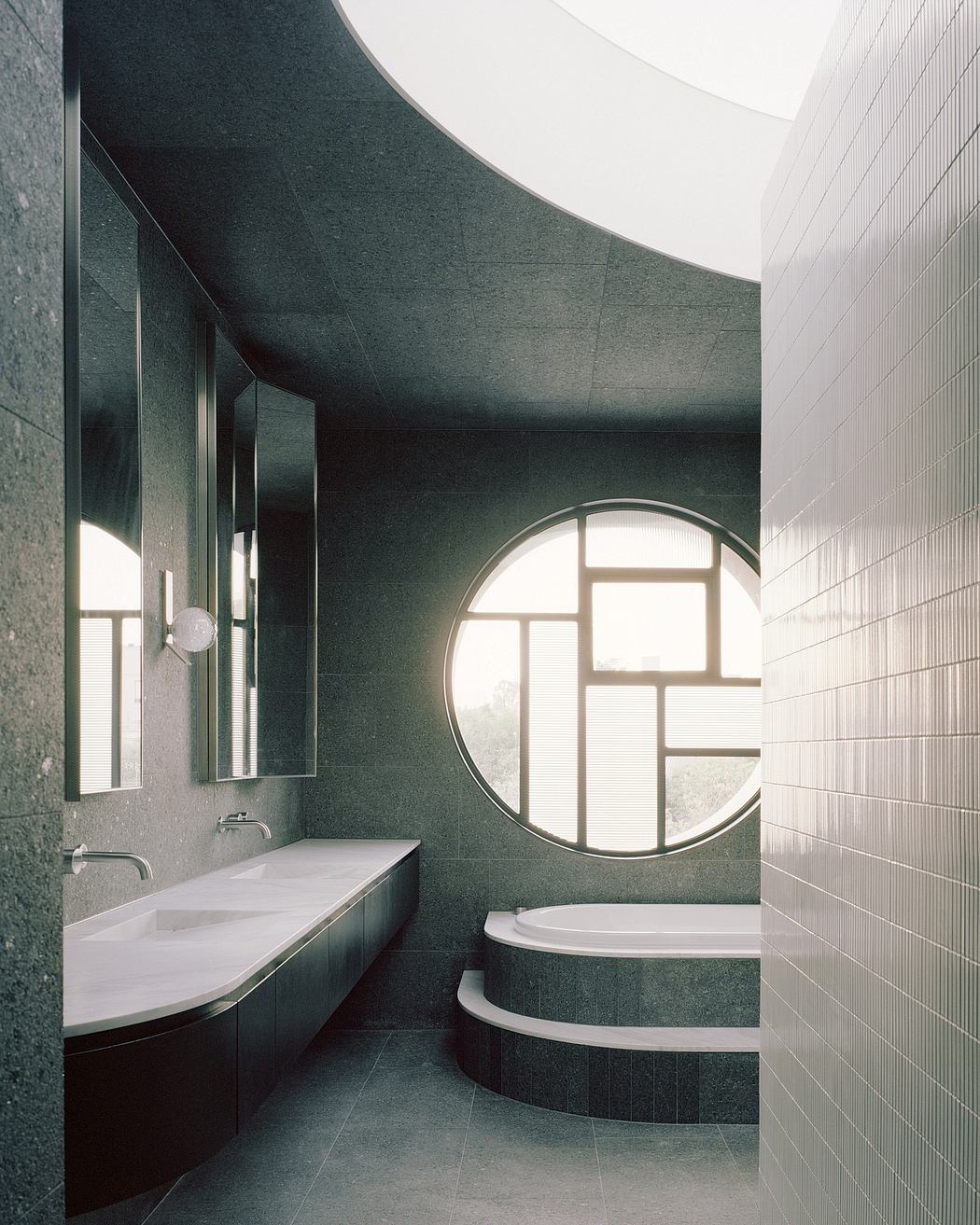 Striking circular window, dark green walls, and modern bathroom fixtures.