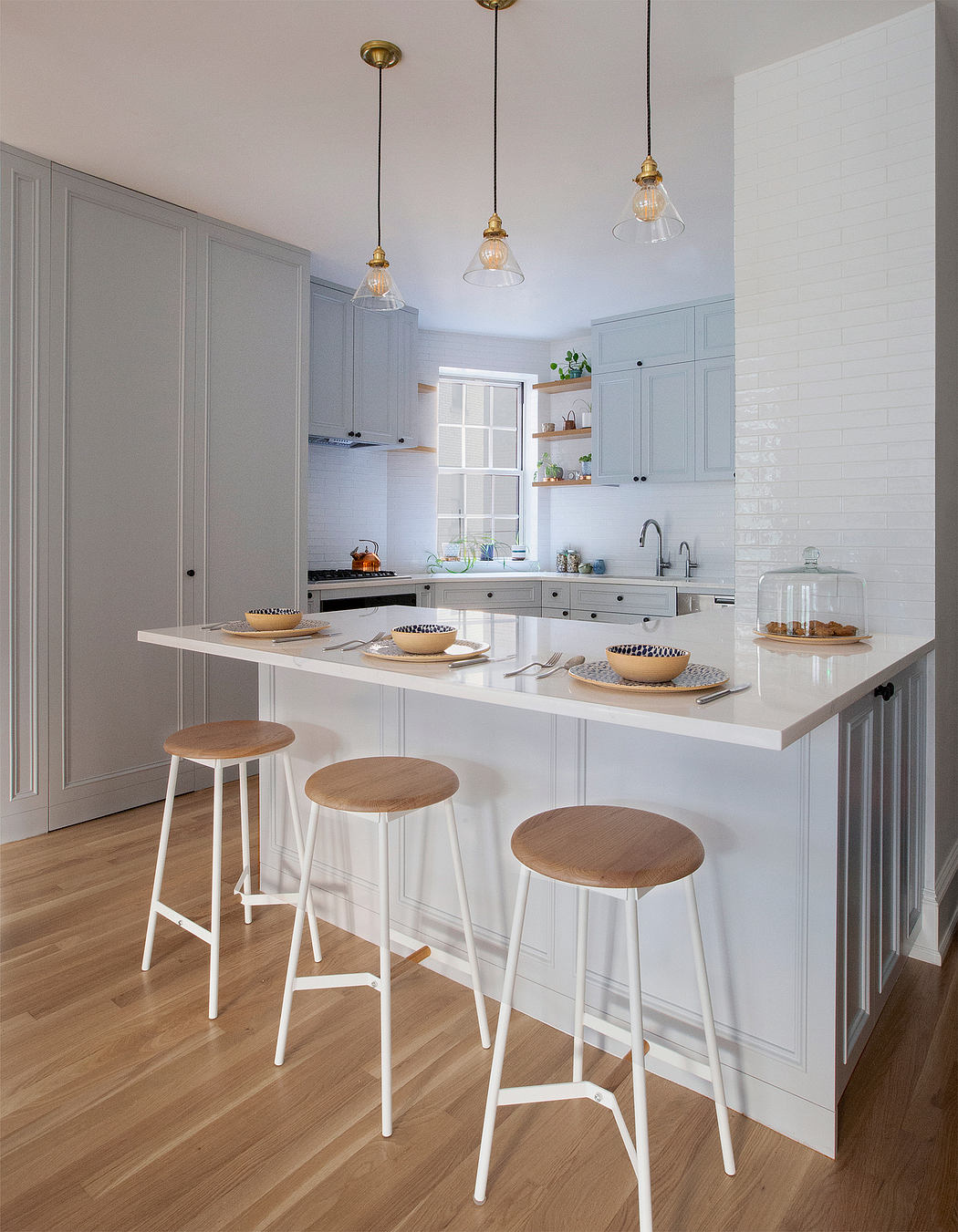 A well-designed kitchen with gray cabinetry, white countertops, and pendant lighting.