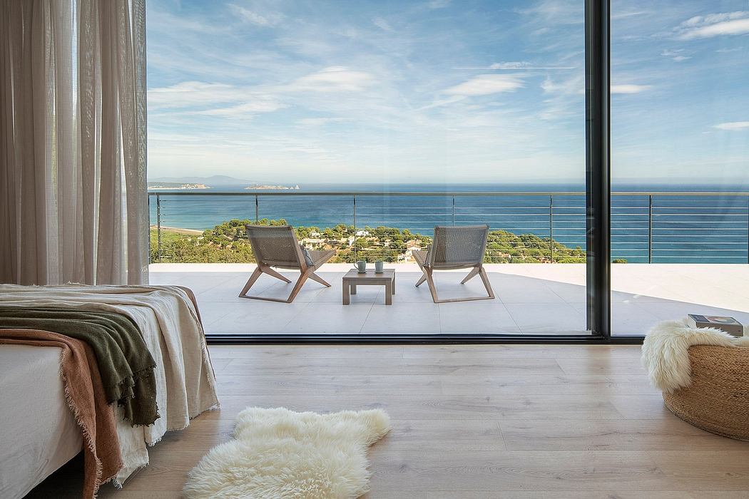Luxurious bedroom with modern furniture and breathtaking ocean view through large windows.