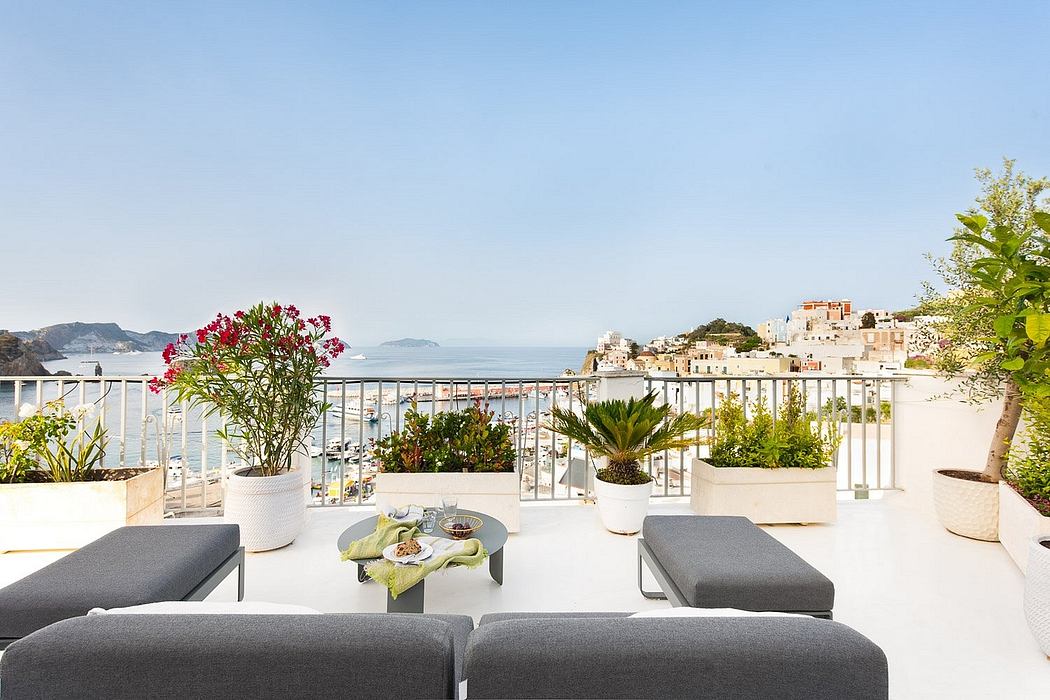 Scenic seaside terrace with modern furniture, potted plants, and sweeping views of the horizon.