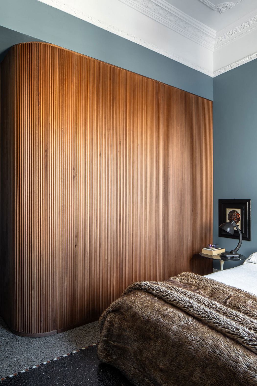 Elegant bedroom with warm, wooden vertical paneling and plush fur blanket.