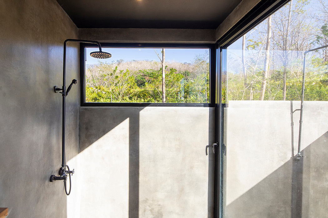 Outdoor shower framing lush greenery through large windows, minimalist concrete design.
