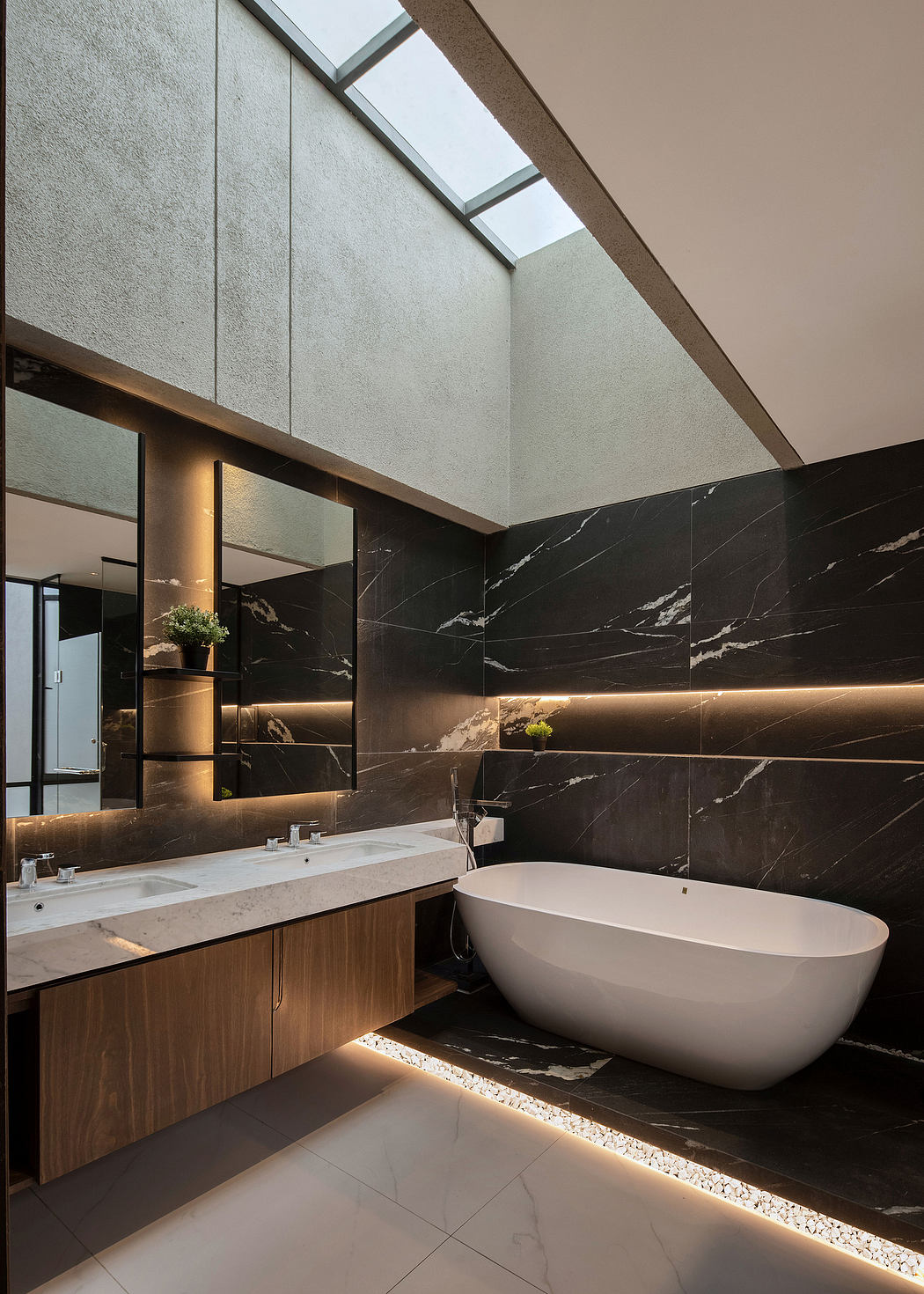 Sleek, modern bathroom with dark marble walls, freestanding tub, and recessed lighting.