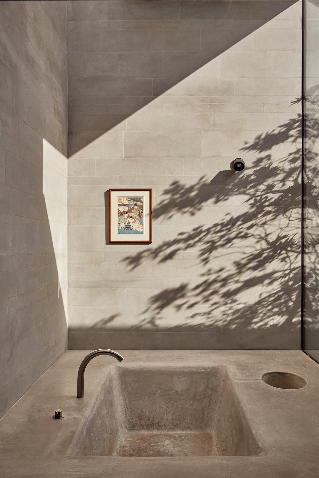 Minimalist bathroom design with framed artwork, concrete walls, and dramatic lighting.