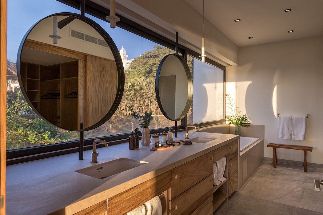 Elegant bathroom with large circular mirrors, wooden vanity, and scenic view.