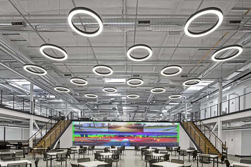 Large open workspace with modern lighting fixtures and a vibrant digital display as the focal point.