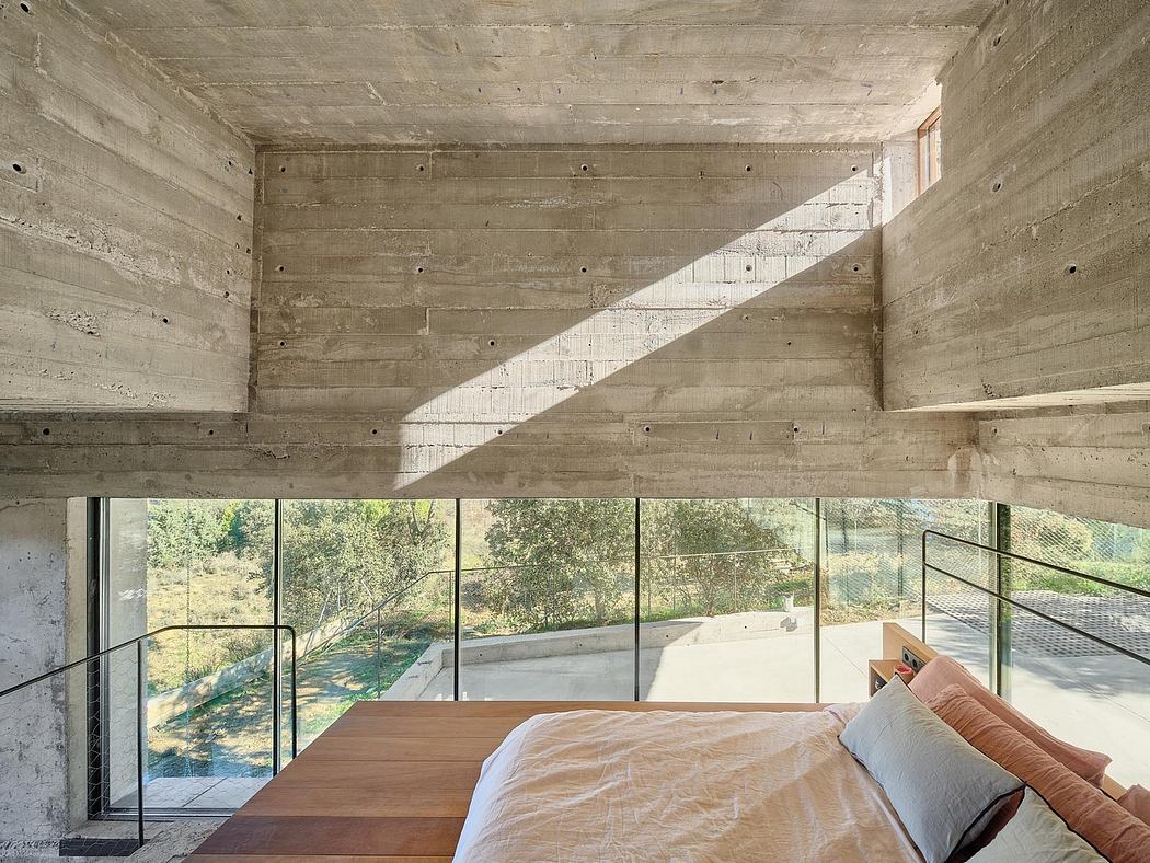 A minimalist bedroom with a concrete ceiling and large windows overlooking nature.