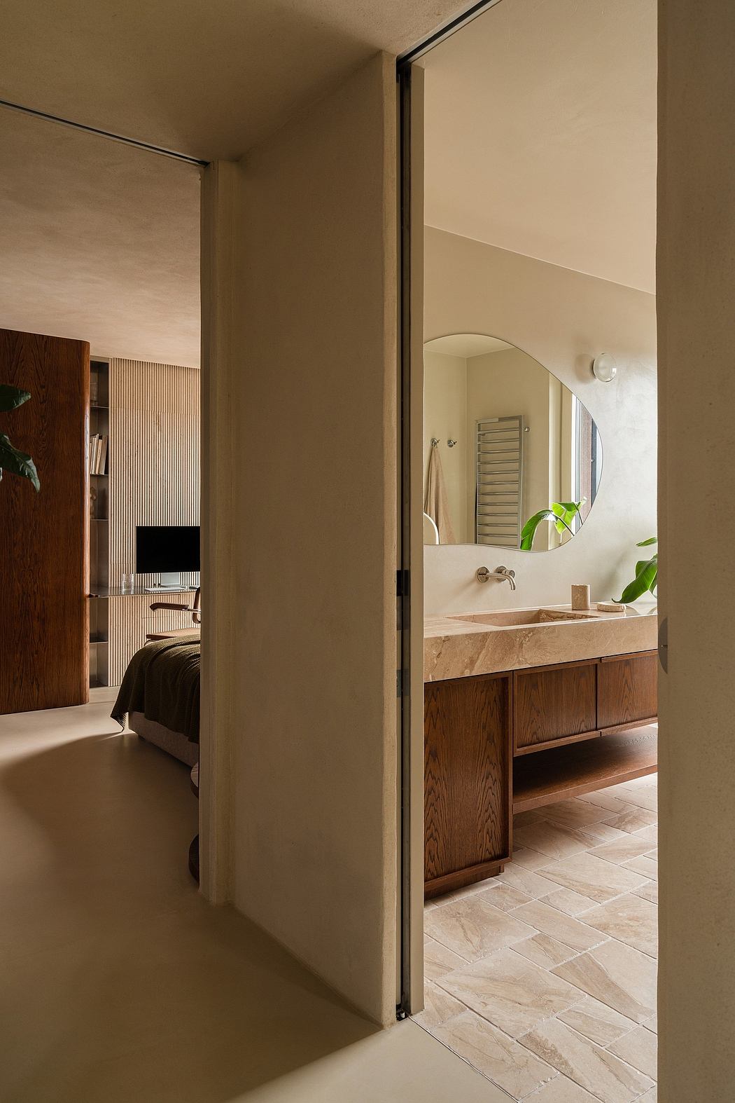 Warm-toned bedroom with modern, minimalist bathroom visible through open doorway.